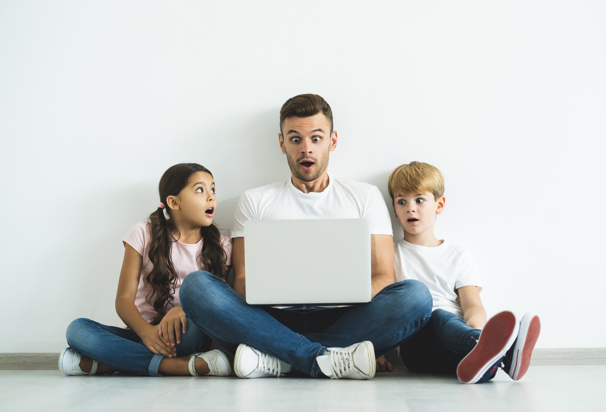 The surprised father and children with a laptop sitting on the floor The surprised father and children with a laptop sitting on the floor