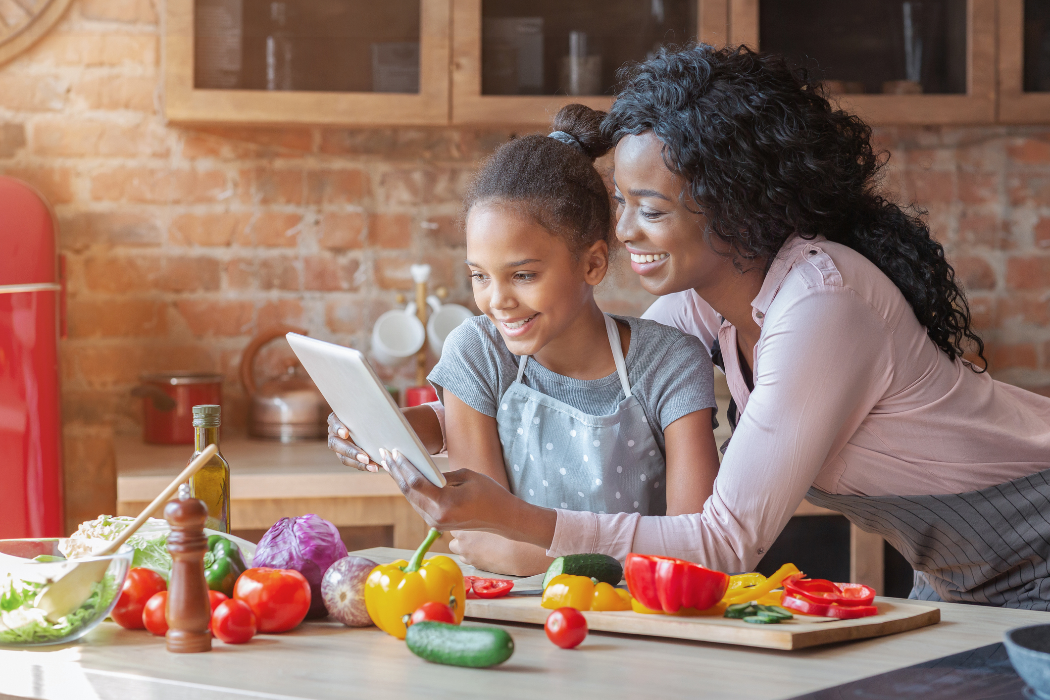 Mommy and daughter reading recipe on tablet at kitchen Mommy and daughter reading recipe on tablet at kitchen