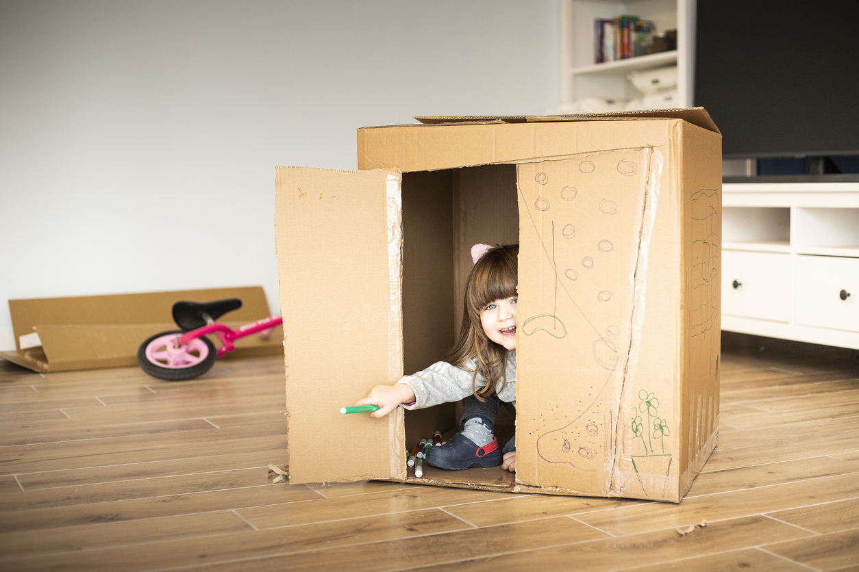 child girl looking out of a cardboard playhouse child girl looking out of a cardboard playhouse