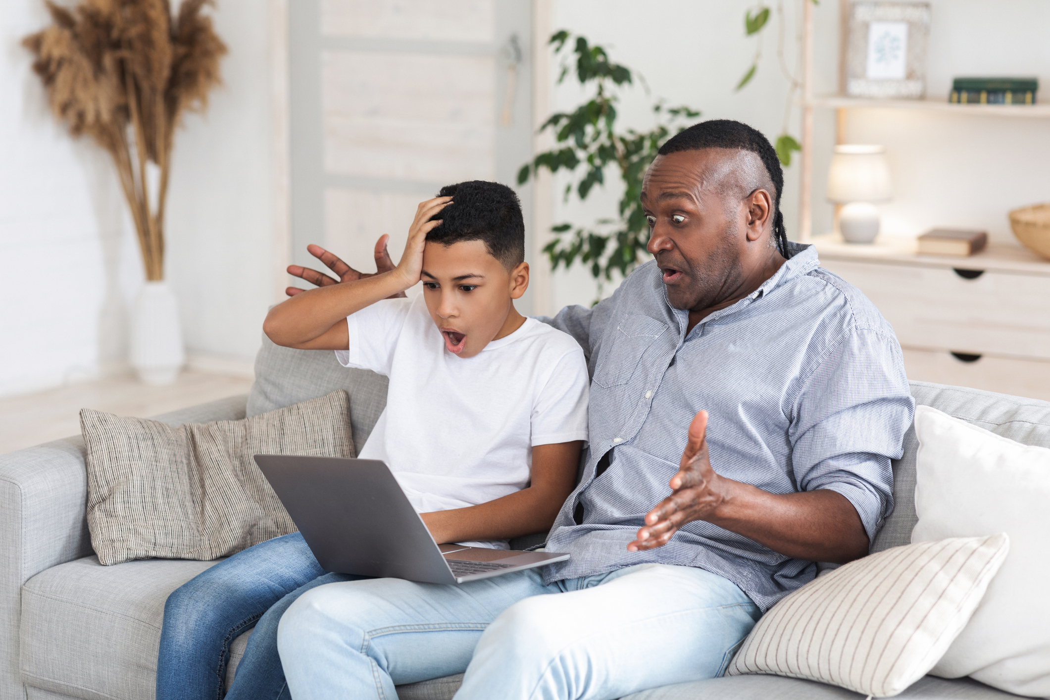African boy and his grandfather looking at laptop screen with shock African boy and his grandfather looking at laptop screen with shock
