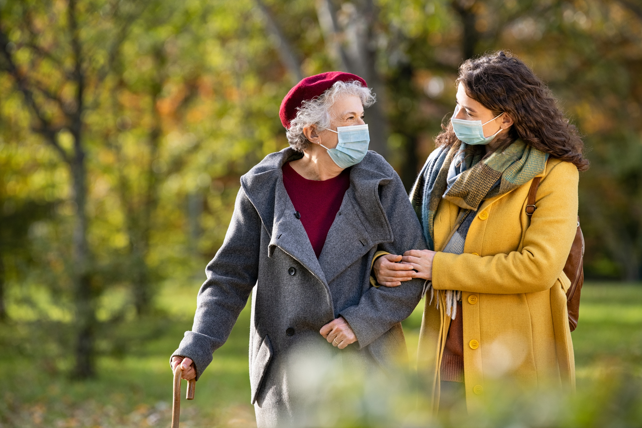 Senior woman with lovely girl wearing face mask at park Senior woman with lovely girl wearing face mask at park