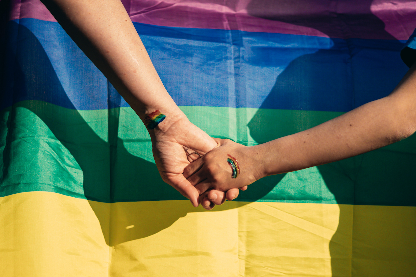 holding hands in front of pride flag holding hands in front of pride flag