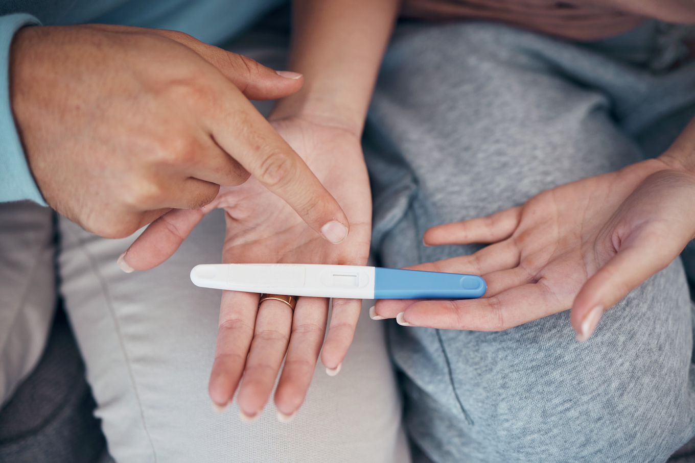 Hands, couple and closeup of pregnancy test, results and waiting for news together in home. Top view, kit and pregnant woman and man family planning for future maternity, ivf fertility and support couple's hands and closeup of pregnancy test
