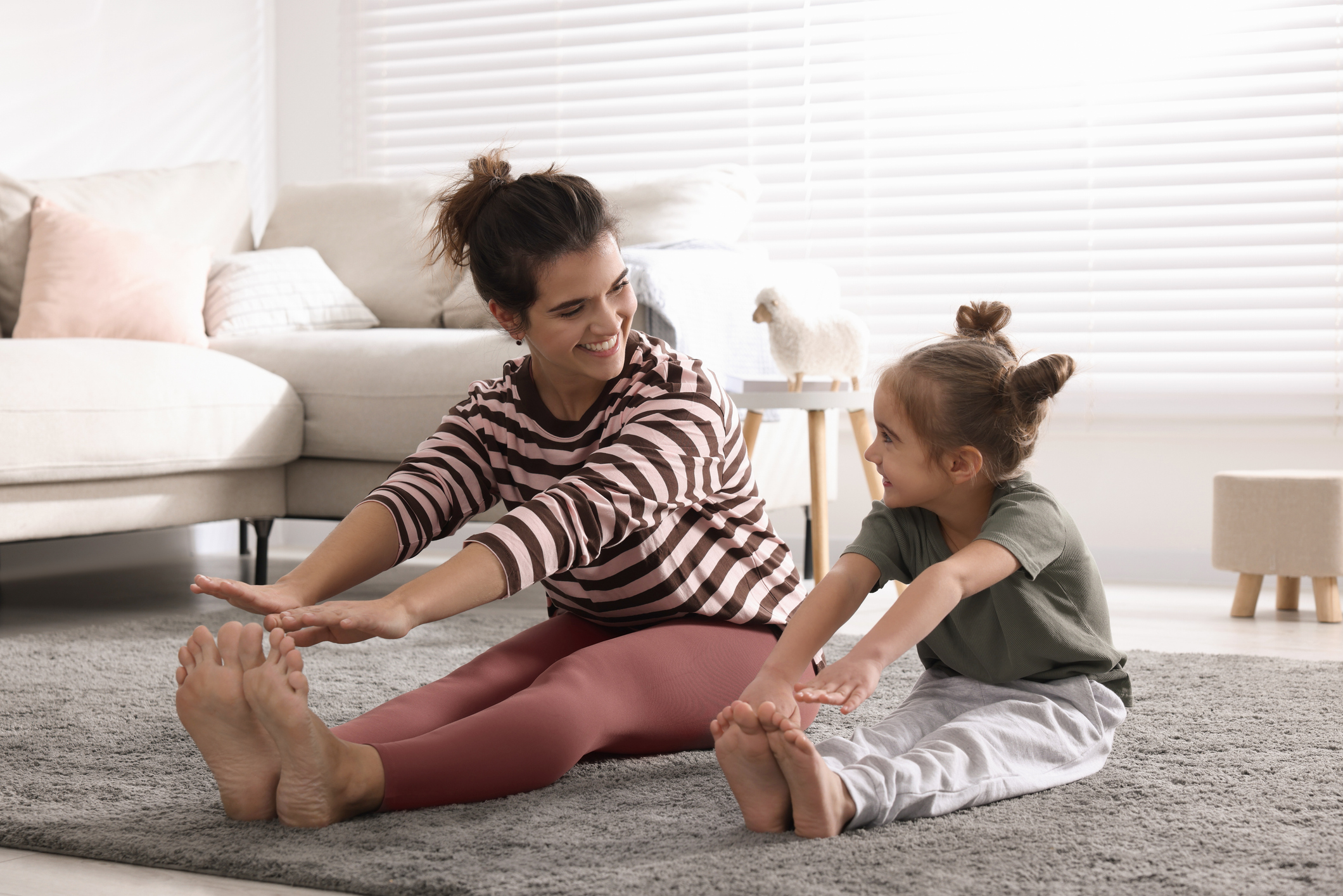 Young mother and her daughter stretching together at home Young mother and her daughter stretching together at home