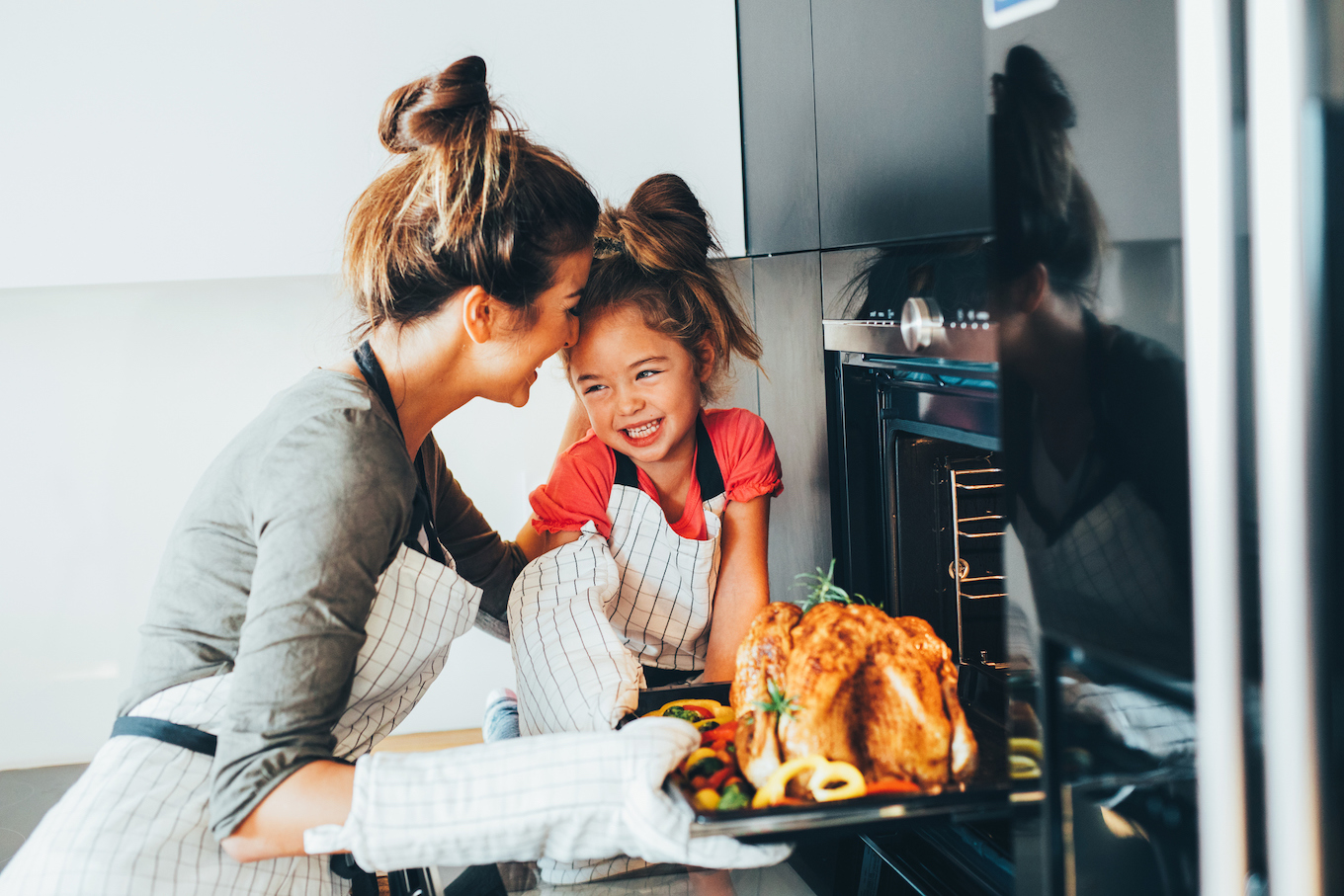 Mom and daughter taking turkey out of the oven Mom and daughter taking turkey out of the oven