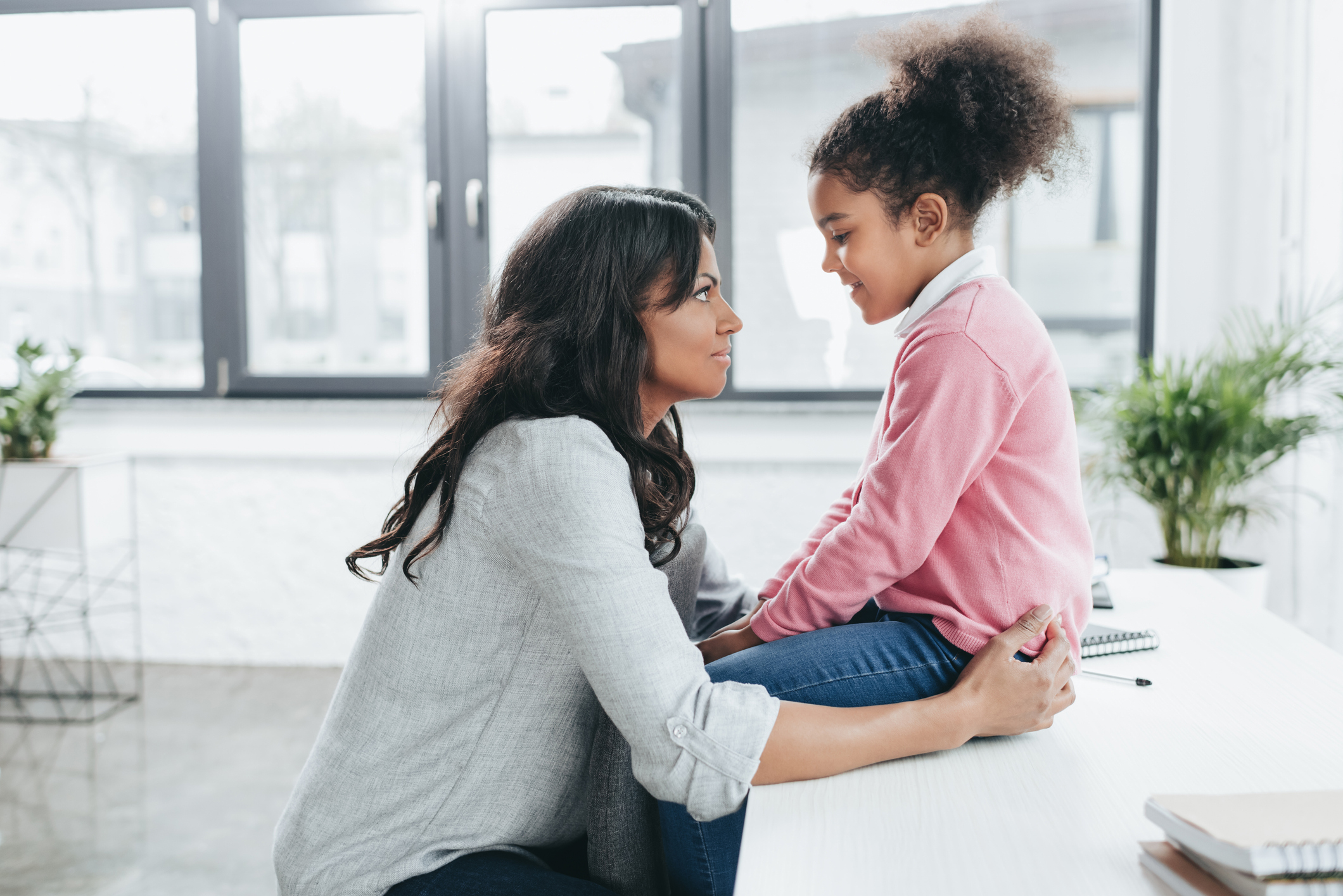 side view of african american mother talking with her daughter indoors side view of african american mother talking with her daughter indoors