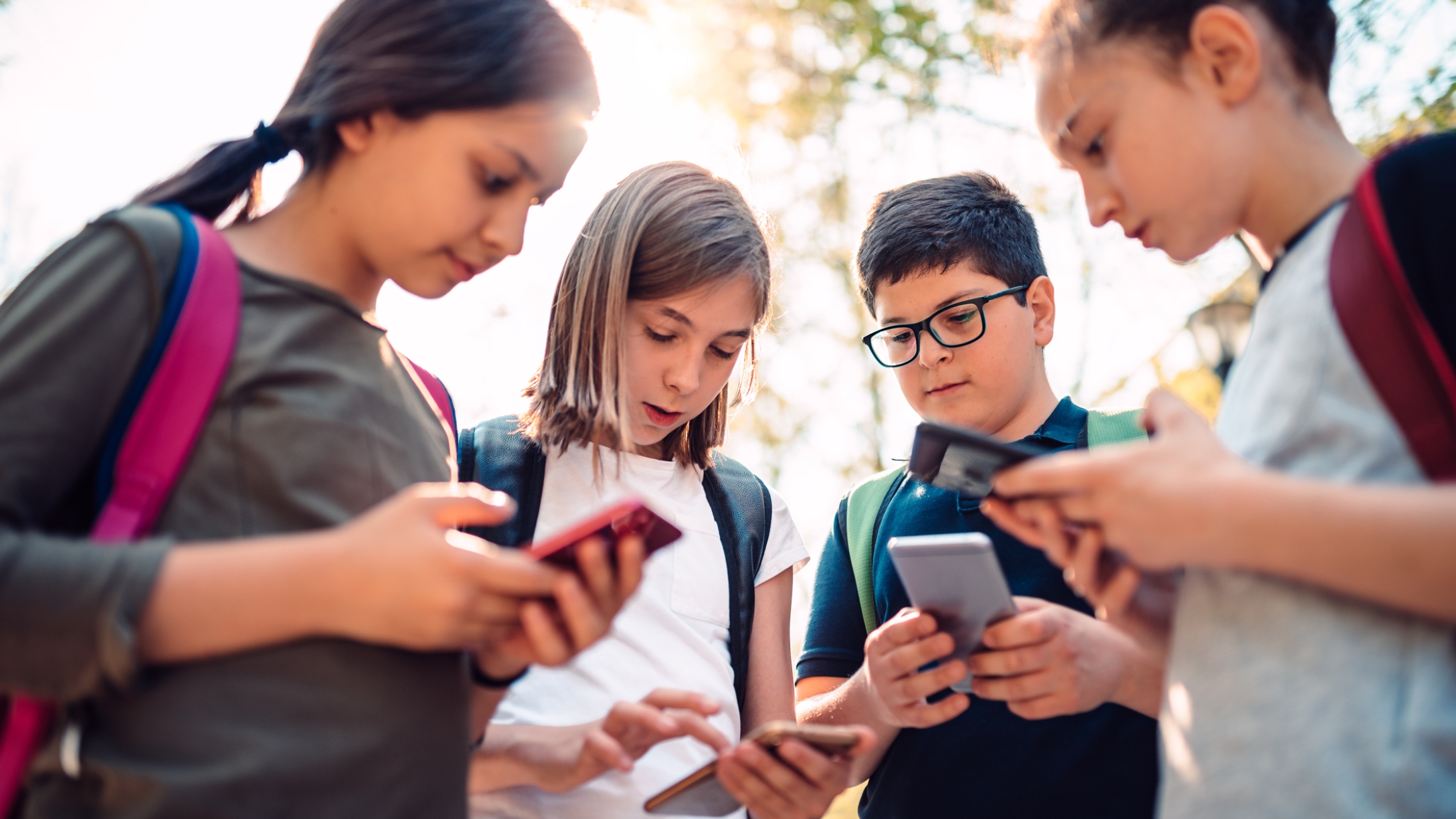 Group of kids playing video games on smart phone after school Group of kids playing video games on smart phone after school